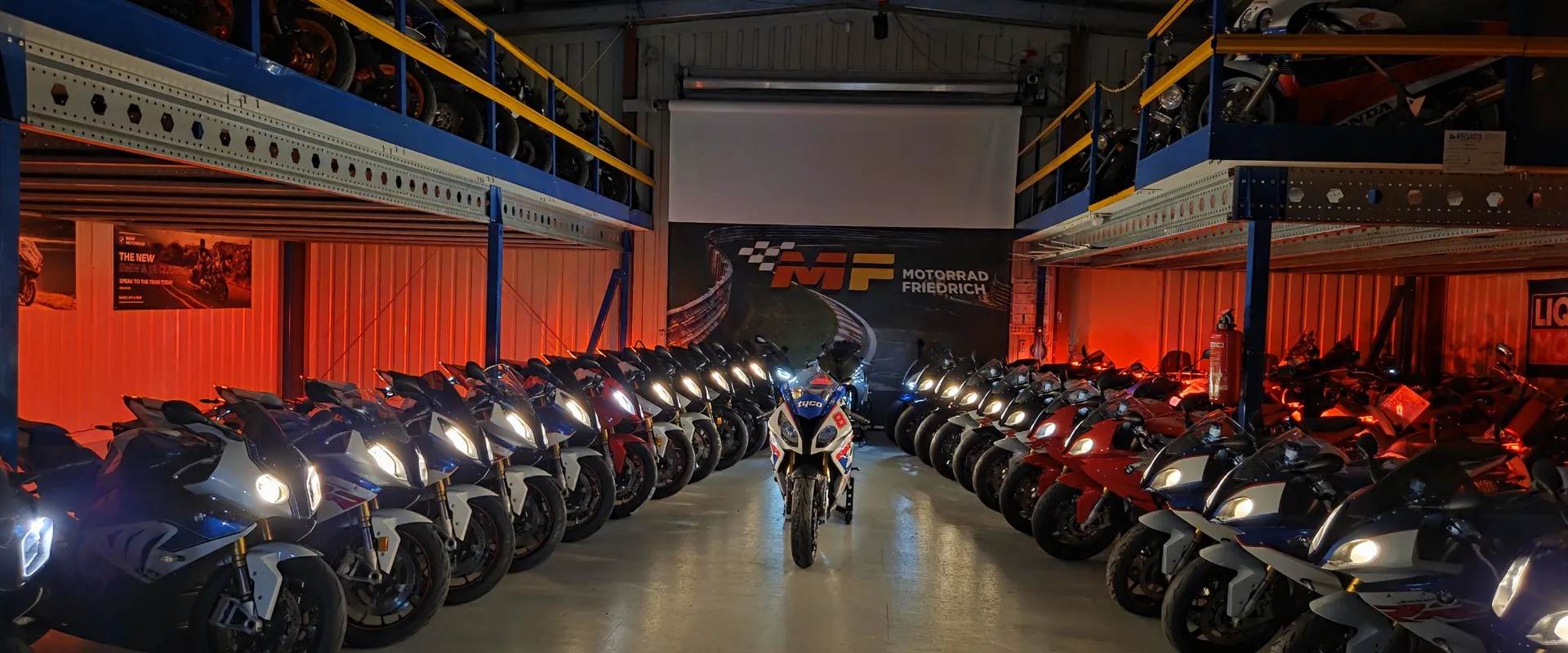 Spalier aus BMW S1000RR K46 mit eingeschaltetem Licht vor dem MF-Banner im Showroom von Motorrad Friedrich
